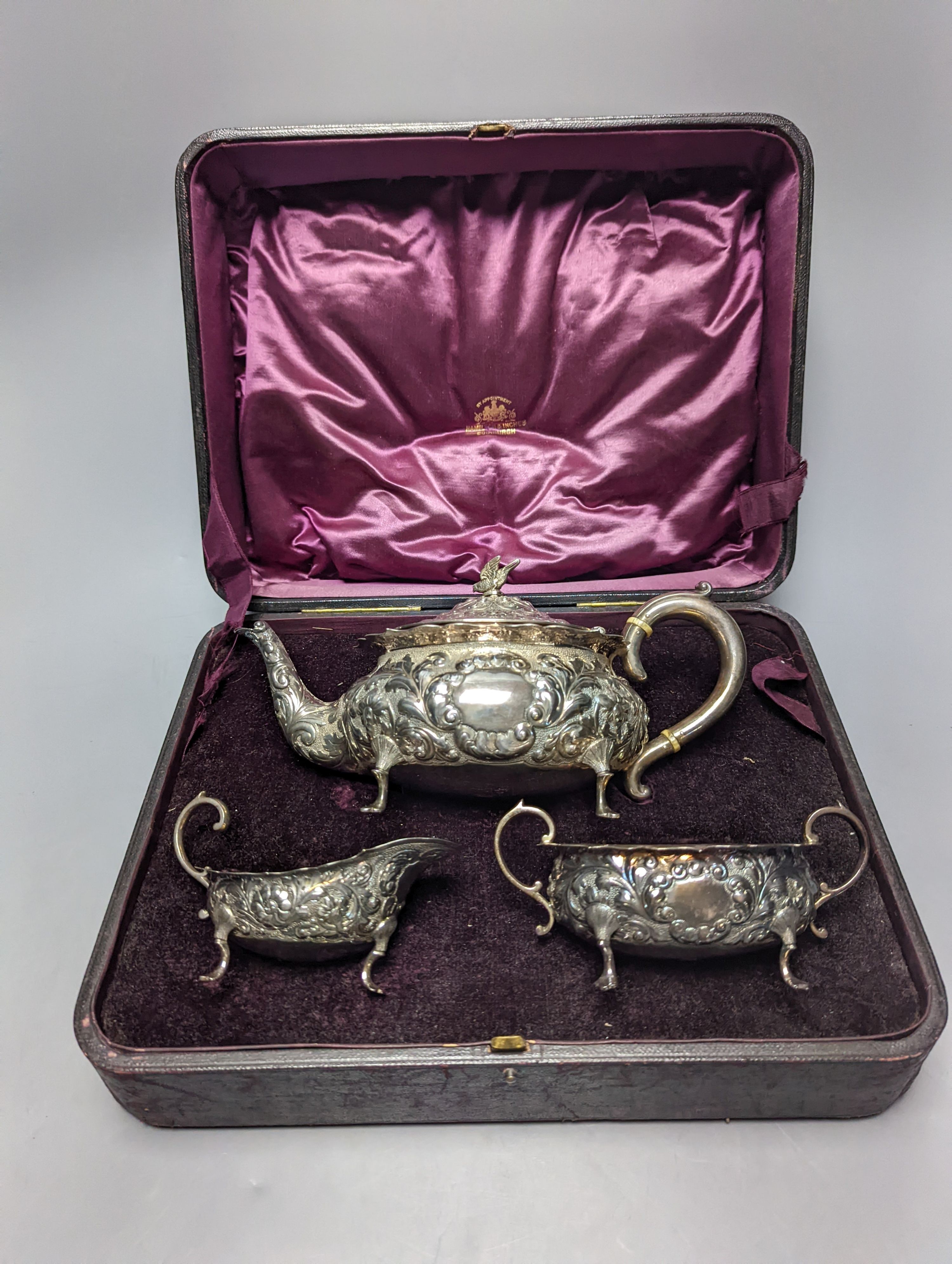A cased late Victorian Scottish repousse silver three piece tea set, Hamilton & Inches, Edinburgh, 1897, gross 21.5oz.